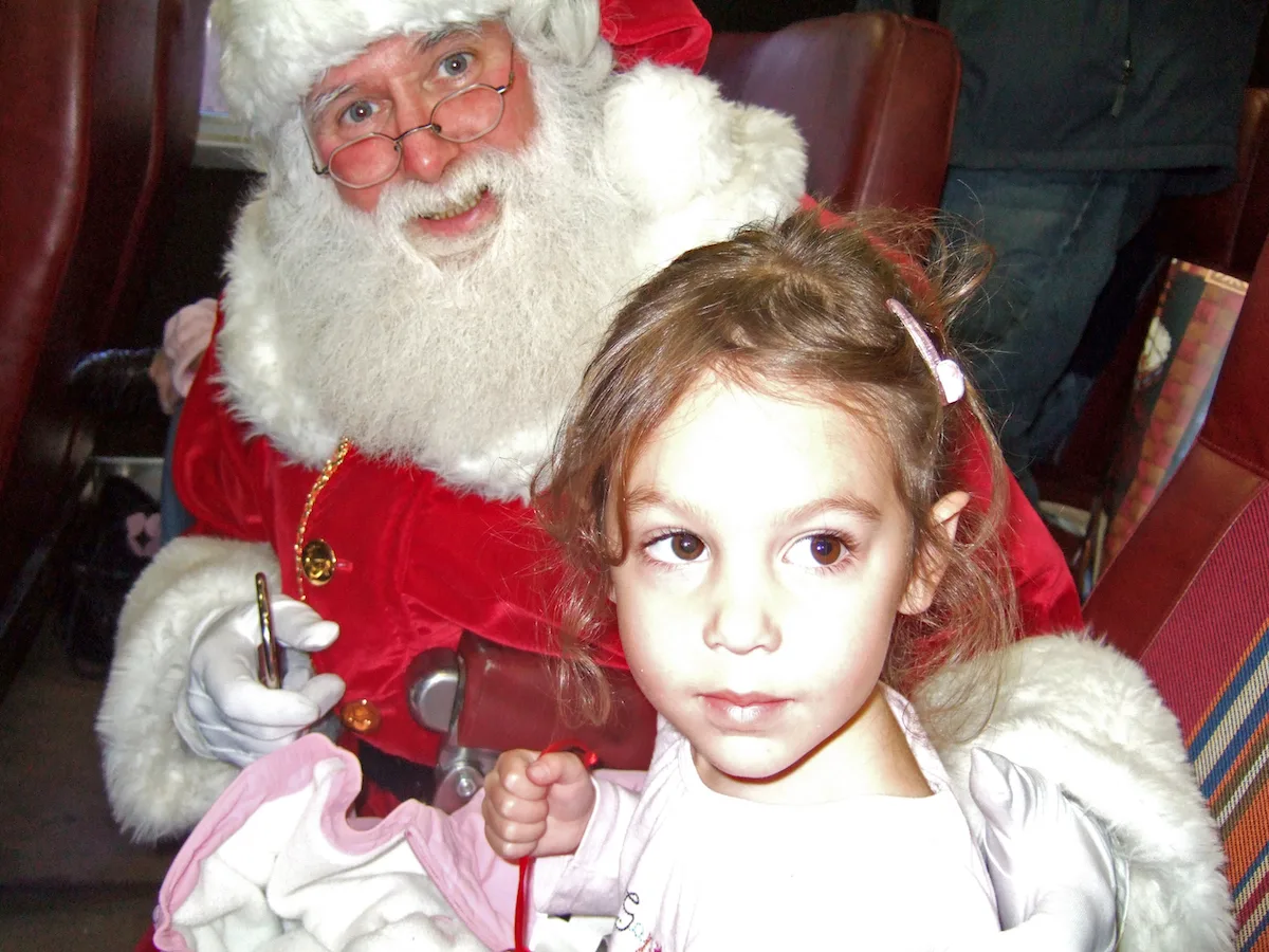 Girl holding Christmas bell with Santa on Polar Express train